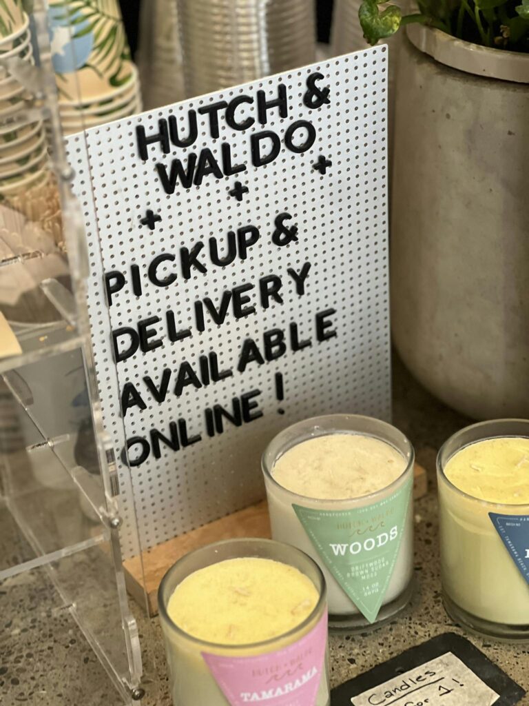 A sign promotes pickup and delivery options at a candle store.